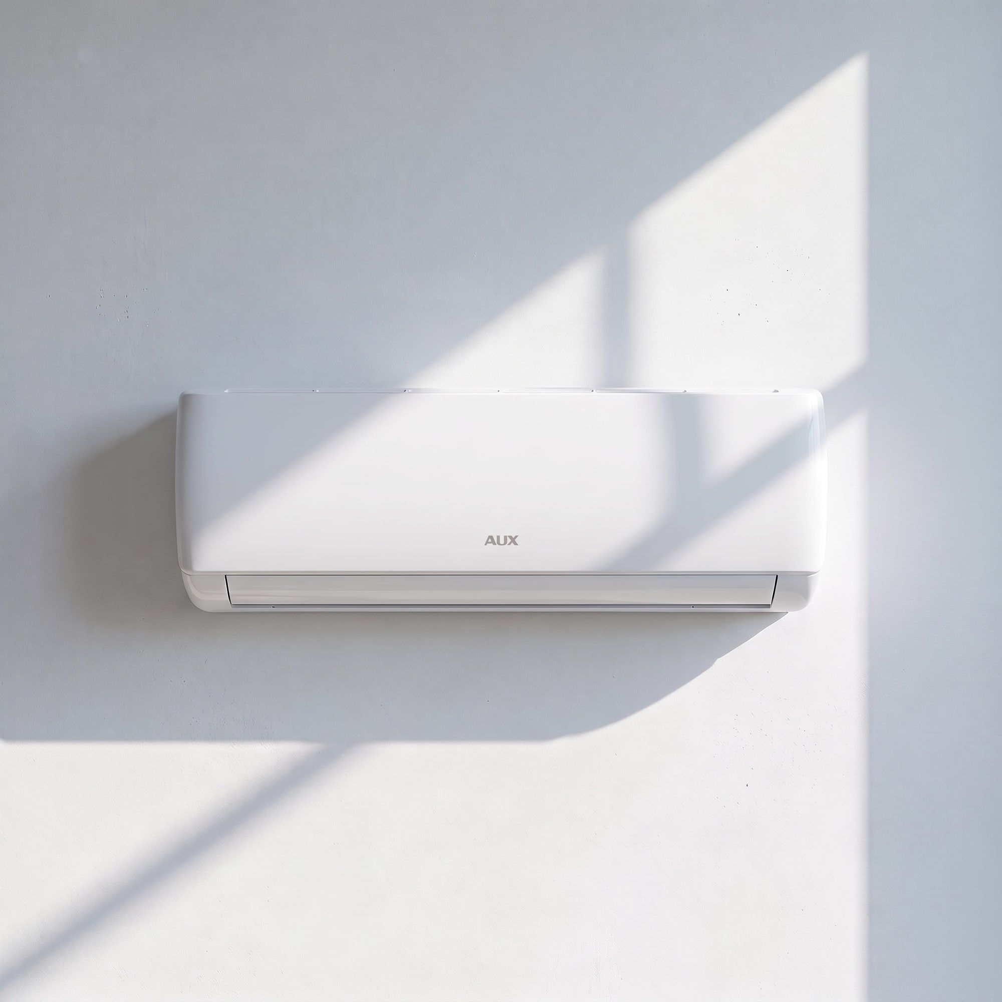 Condizionatore AUX a parete su un muro bianco, con la luce del sole che entra di taglio