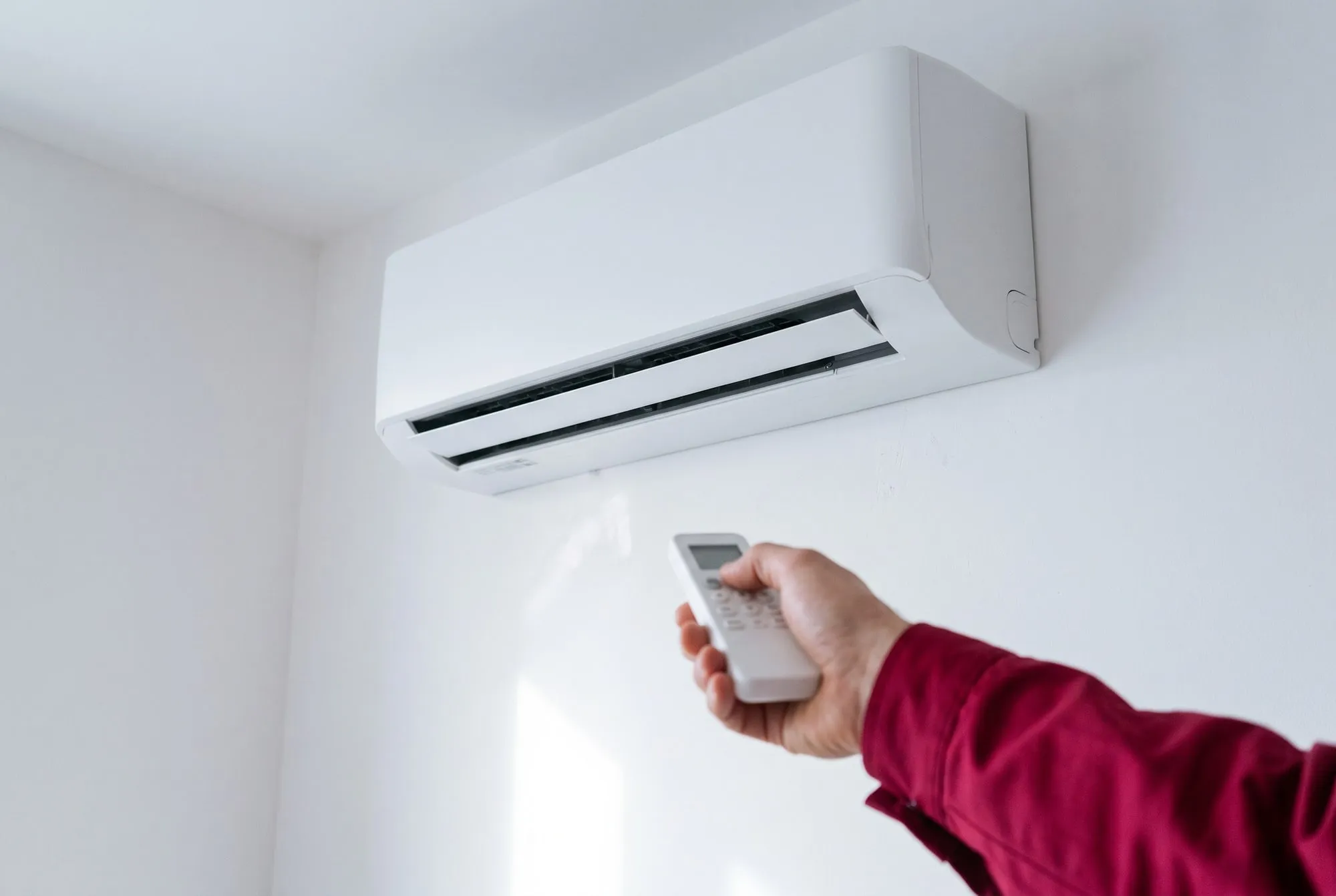 Mano con il telecomando orienta verso il basso l’aletta di un climatizzatore a parete